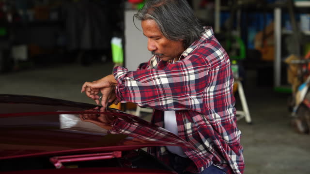 Senior technician man repairing car engine in garage