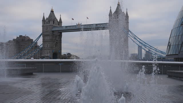 Slow Motion. A view of a fountain stream with the Tower Bridge behind it.