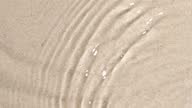 istock Slow motion closeup water surface texture splash and ripples on sand background 1372277639