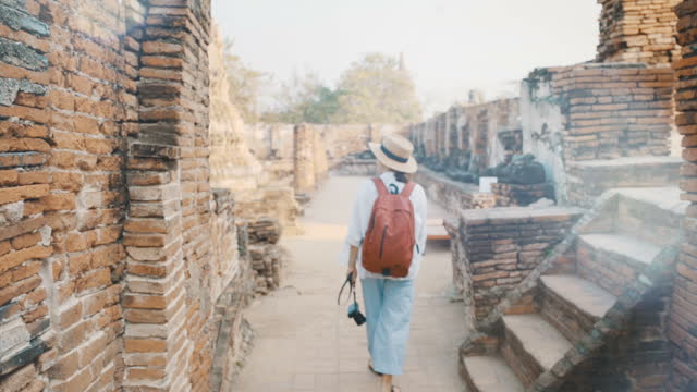 Slow motion female tourist with photo camera walking through ancient ruins