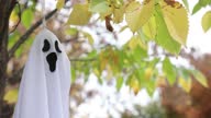 istock Small Halloween ghost toy suspended in colored tree in light wind 1346605809