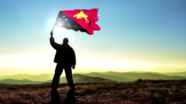 Successful silhouette man winner waving Papua New Guinea flag on top of the mountain peak, Cinemagraph LOOP background