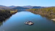istock The ferry transports cars across the blue Yenisei River against the backdrop of mountains. Filming from a drone. 1294195395