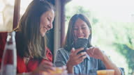 istock Two multi-ethnic female friends enjoying their time in cafe and using smart phone together 1340325457