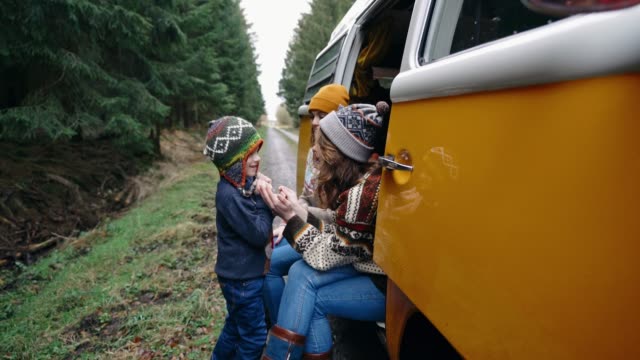 Two women and little boy sitting in retro camper van