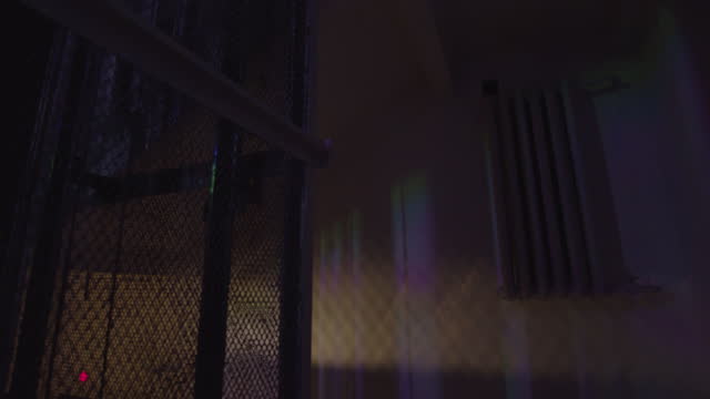 Vintage elevator descending in a dark building with flashing colorful light bulb that lighting old walls. Stock footage. Interior of a stylized night club