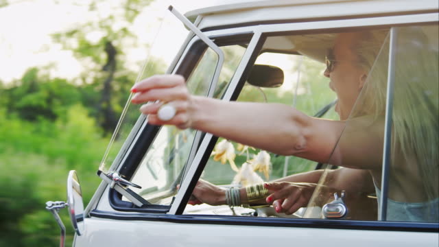 Woman holding hand out of window while driving