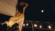 istock SLO MO Woman in long yellow dress walks on a deck of a sailboat sailing at night 1366416631
