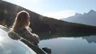 istock Woman opens car door to enjoy beautiful mountain scene 1348990690