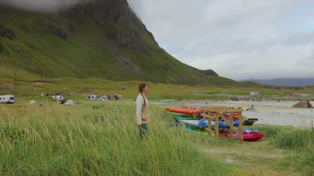 Woman traveler contemplating morning by the scenic mountain beach on Lofoten Islands