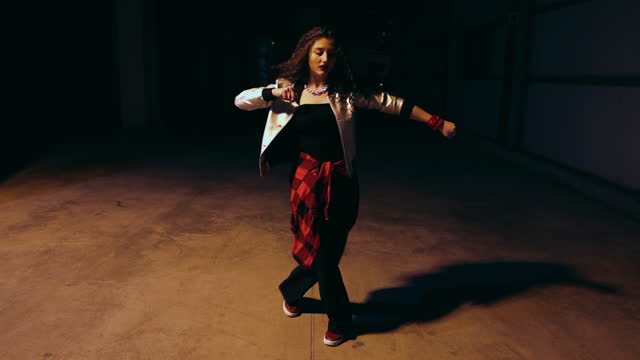 Young street styled woman dancing in the dark